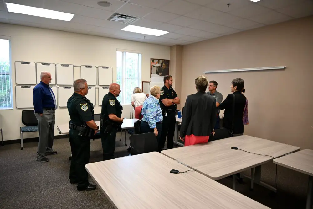 Members of the Flagler County School Board in a huddle with Flagler County Sheriff's deputies before this evening's meeting as they were being cautioned--and directed--on following deputies' directions in case the meeting turned chaotic. It was an unprecedented caution. (© FlaglerLive)