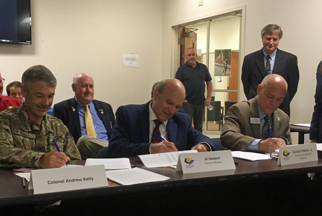 Col. Andrew Kelly of the U.S. Army Corps of Engineers signing what amounts to a 50-year, $100 million agreement to 'renourish' 2.6 miles of dunes in Flagler Beach. Signing along was County Attorney Al Hadeed and Flagler County Commission Chairman Donald O"Brien. The ceremonial signing took place at the Government Services Building in Bunnell Tuesday. (© FlaglerLive)