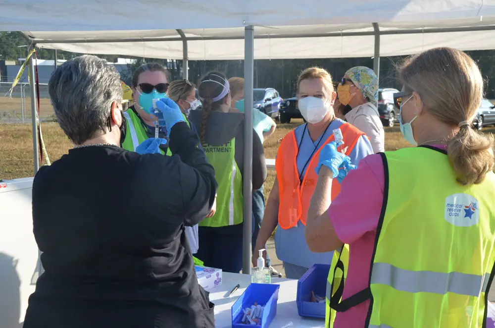 Public health and medical staffers preparing second-dose covid-19 vaccine shots this morning at the Flagler County airport grounds. (© FlaglerLive)