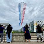 Residents watch French air force jets fly over a Paris suburb during the Bastille Day military parade on July 14, 2023.