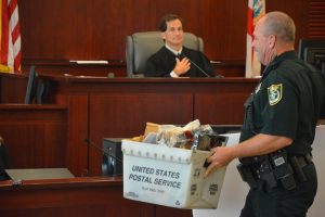 A bailiff takes the bin of evidence to the jury room for deliberations. Deliberations lasted less than half an hour, and little evidence was sought. (© FlaglerLive)