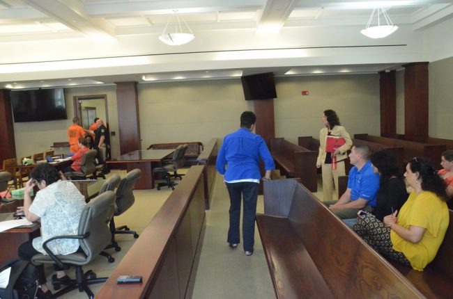 Some of Rushing-Griffen's victims watch him leave the courtroom after sentencing. The victim's advocate is walking away from the first row, Assistant State Prosecutor Melissa Clark is standing between the aisles. (© FlaglerLive)