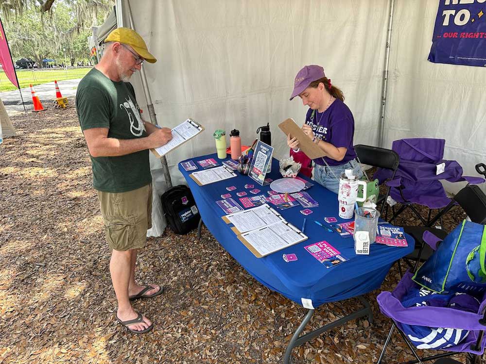 Roxanne Perret, an organizer with People Power for Florida, registers Mark Wendell to vote at a May festival in Orlando. Third-party voter registration groups have been threatened with fines and workers with jail time if they violate new state laws.