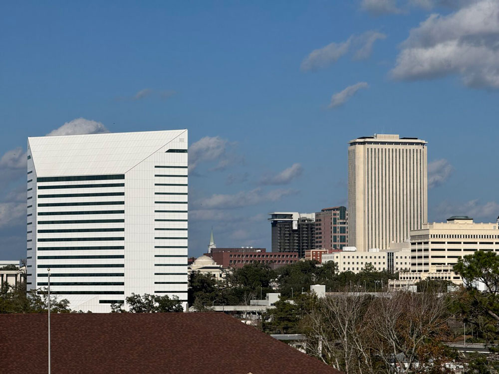 The Turlington Building, which houses the Florida Department of Education, stands in the foreground, with the Tallahassee skyline, including the Capitol building, beyond.