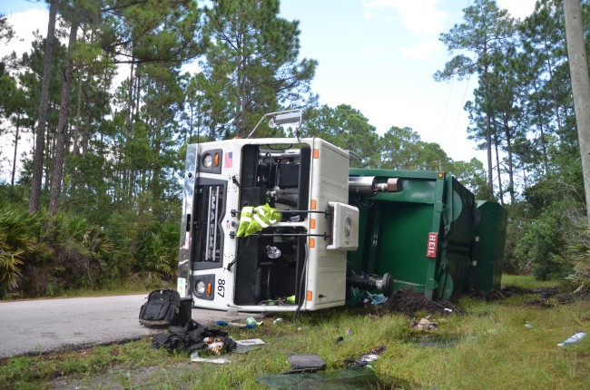 The Waste Pro  turck overturned as if was driving around the bend on Reybury Lane in Palm Coast. Click on the image for larger view. (c FlaglerLive)