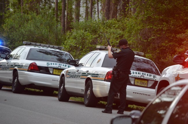 A Flagler County Sheriff's deputy examines one of the rifles seized on the incident on Utah Place. Click on the image for larger view. (© FlaglerLive)