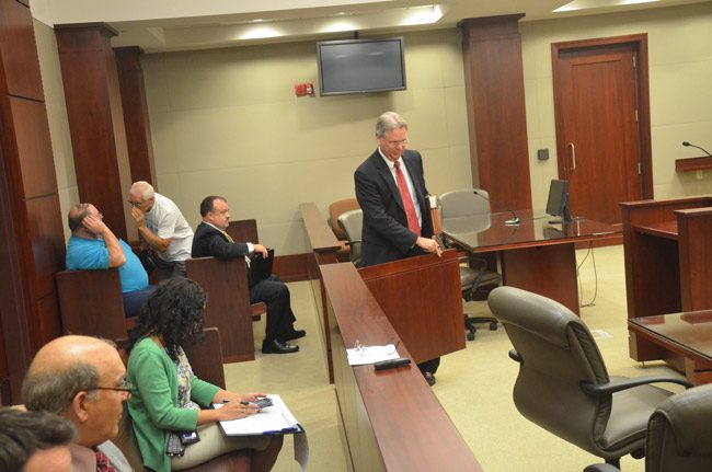 Kevin Kulik, center, is the fourth lawyer Weeks has retained since her indictment. She was not at the meeting today. John Ruffalo, an ally, is whispering to Weeks's husband, Duane. In the foreground sat Al Hadeed, the county attorney. (© FlaglerLive)