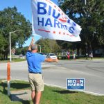 Peter Wentworth waving a Biden-Harris flag on Palm Coast Parkway on Election Day, across the street from Trump supporters. (© FlaglerLive)