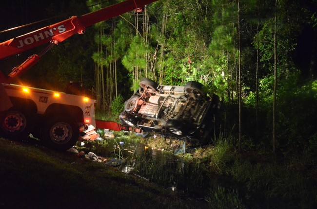 A Class C wrecker truck was called in to lift the SUV straight up and enable the medical examiner to retrieve Joseph Drenner's body, which had been trapped under the vehicle. Click on the image for larger view. (© FlaglerLive)