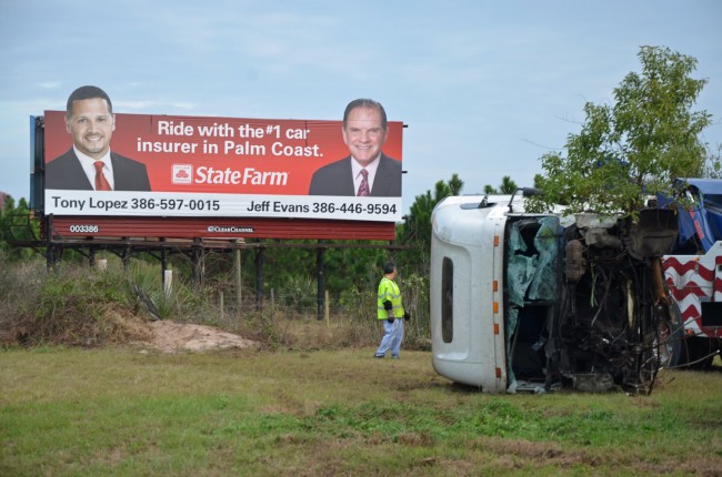 The cab portion of the semi truck just after it was fished out of a pond at the bottom of a 30-foot ravine, below the billboard. And no, State Farms is not an advertiser. Click on the image for larger view. (© FlaglerLive)