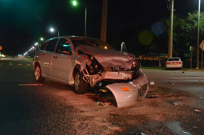 The Ford Focus was struck head-on, ending up facing opposite the flow of traffic on Palm Coast Parkway. The Kia Optima struck the utility pole, to the right in the distance, after the collision with the Ford. Click on the image for larger view. (c FlaglerLive) 
