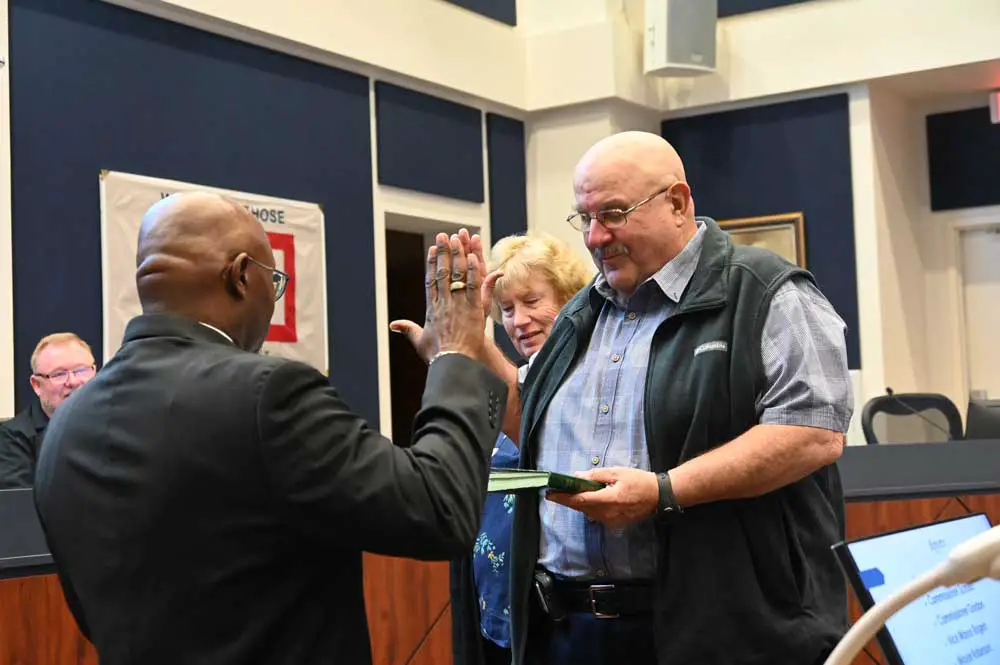 They only look like they're high-fiving: Bunnell City Manager Alvin jackson administering the oath of office to Pete Young Monday evening, with Young's wife of 44 years, Julie Young, at his side, and John Rogers to the left, looking on from the dais. (© FlaglerLive)