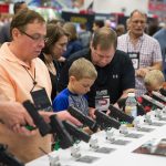 NRA conventiongoers, like these at the gun group’s 2018 big meeting, browse firearms exhibits.